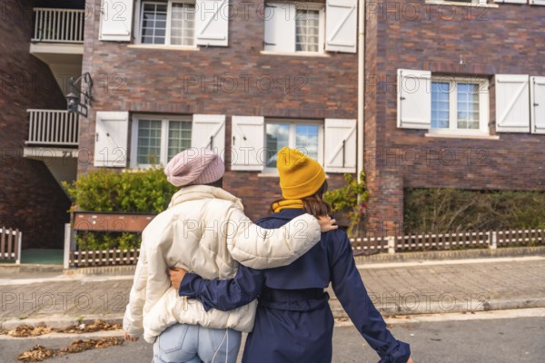 Two friends walking arm in arm down a european city street, enjoying an autumn day together in warm