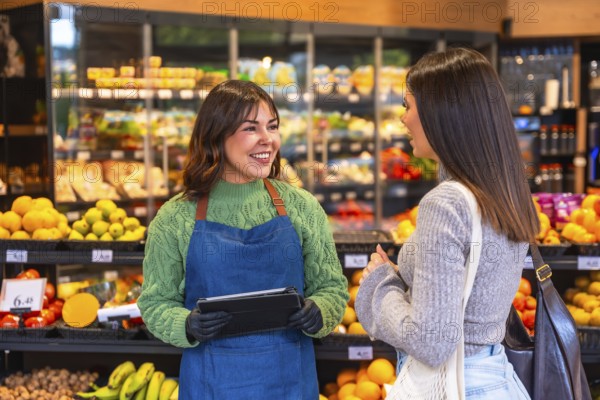 Grocery store employee with a tablet providing excellent customer service and smiling while talking