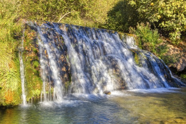 Fascinating waterfall flowing over green moss rocks into a natural basin, El Kelaa wild stream in