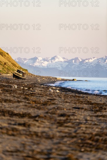 Boat on Anchor Point beach on Cook Inlet in the evening light, snowy mountain peaks, Anchor River