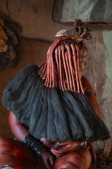 Elderly Himba woman showing her hair and jewelry, in a hut, traditional Himba village, Kaokoveld,