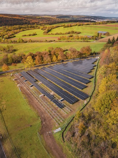 Aerial view of a large solar plant in an autumn landscape with fields and trees, PV