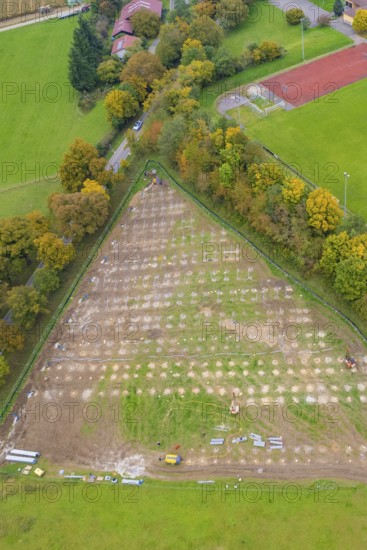 Parceled green area in triangle shape, surrounded by trees and infrastructural facilities, PV