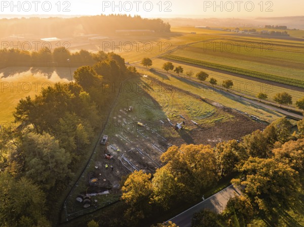 Morning landscape with warm lighting and trees next to construction, PV Freifaechenanlage