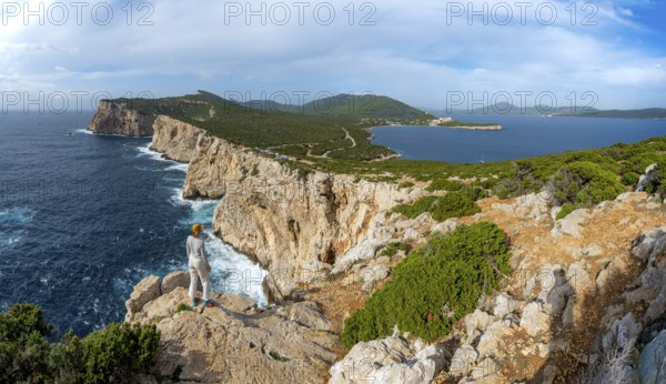 Tourist enjoying the view of steep cliffs by the sea, coastal landscape, cliffs on the Capo Caccia