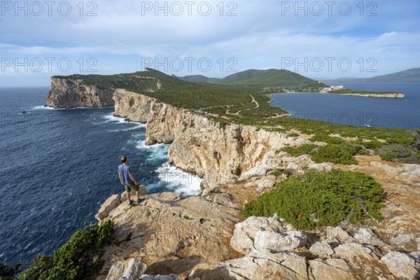 Tourist enjoying the view of steep cliffs by the sea, coastal landscape, cliffs on the Capo Caccia