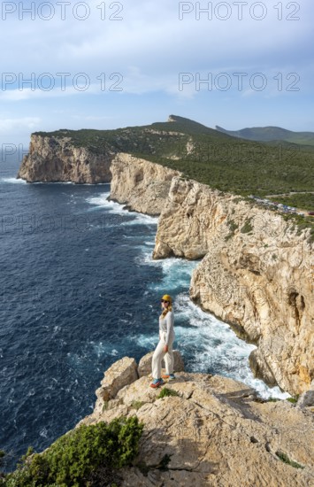 Tourist enjoying the view of steep cliffs by the sea, coastal landscape, cliffs on the Capo Caccia