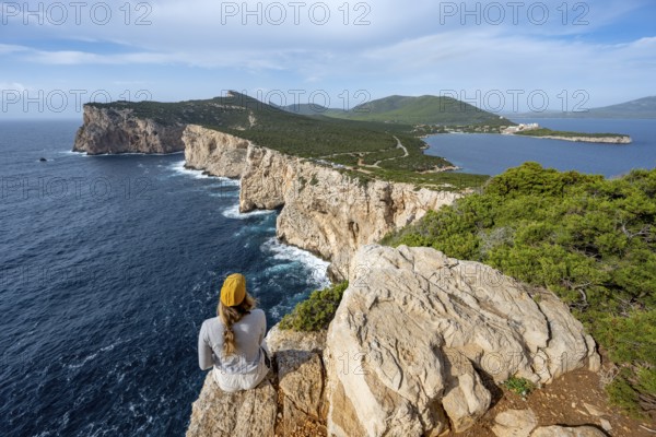 Tourist sitting on the edge of a steep cliff, view of steep cliffs by the sea, coastal landscape,