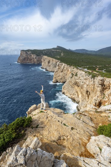 Tourist stretches her arms in the air, view of steep cliffs by the sea, coastal landscape, cliffs