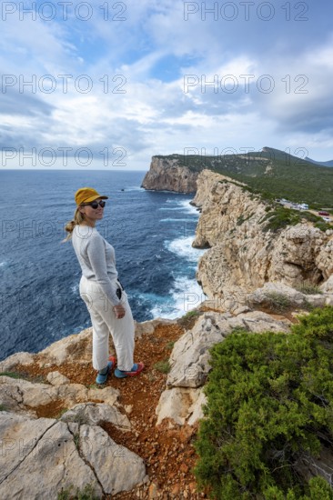 Tourist enjoying the view of steep cliffs by the sea and the rocky island of Isola Foradada, cliffs