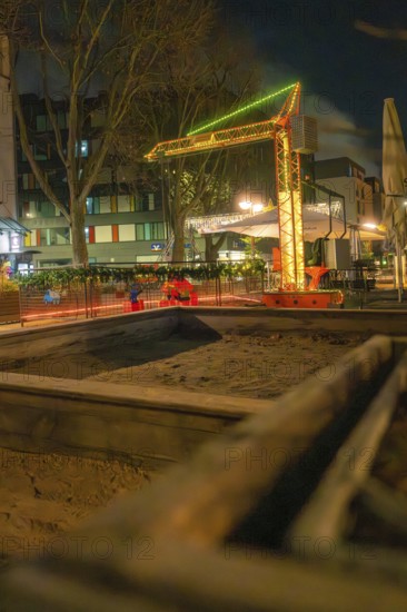 Evening street scene with illuminated construction crane and surrounding buildings, Sindelfingen,