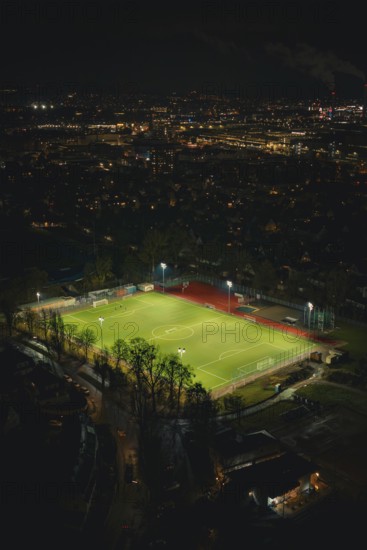 Illuminated soccer field in an urban area at night with glowing city lights, Sindelfingen,