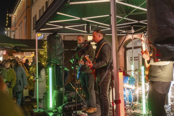 Live music performance on a stage in a festively illuminated market, Christmas market 2025, Nagold,