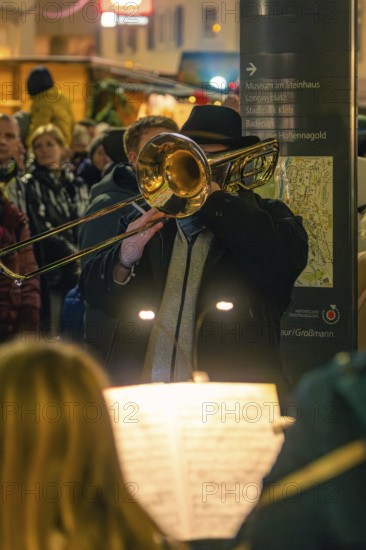 Musician plays trombone at an evening concert in a festive setting, Christmas market 2025, Nagold,