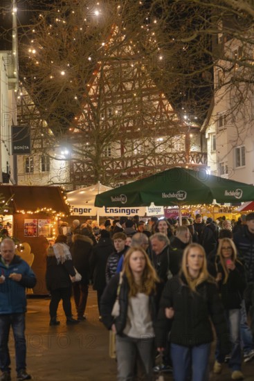 People stroll through a well-visited, festively lit Christmas market, Christmas market 2025,