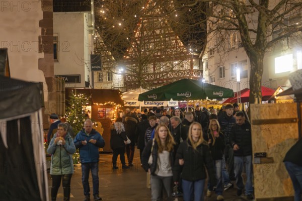 Lively Christmas market with numerous visitors and illuminated half-timbered houses, Christmas