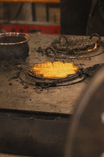Freshly baked waffles on a hot iron in a Christmas setting, Christmas market 2025, Nagold, Black