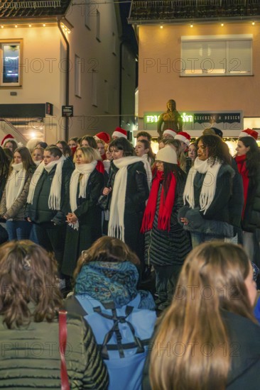 Choir sings in the evening in a Christmas atmosphere, surrounded by spectators, Christmas market