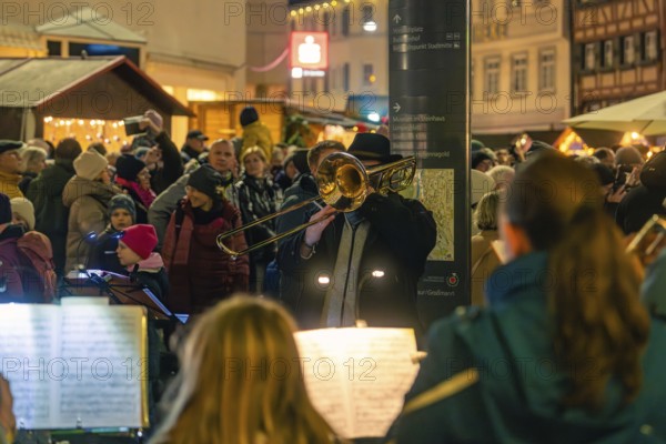 Street musicians play outdoors on a busy shopping street at night, Christmas market 2025, Nagold,