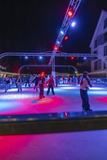 Colourful lights on an ice rink at night, people skating and friendly togetherness, Christmas