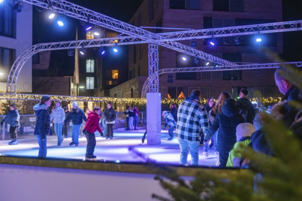People skating on an illuminated area surrounded by a winter atmosphere, Christmas market 2025,