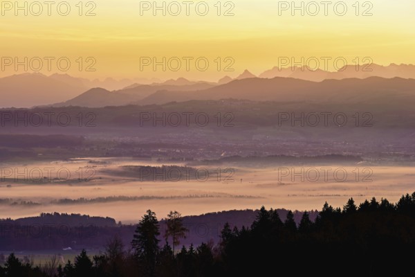 View from Horben of the Reuss Valley covered in fog, behind it the Glarus Alps in the light of the