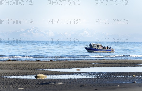 View over Cook Inlet to white mountain peaks of the Aleutian Range, motor boat on the ocean, Anchor