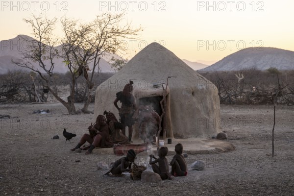 Himba woman and children sitting in front of a hut, sunrise, traditional Himba village, Kaokoveld,