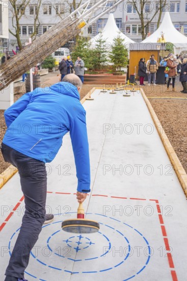 Man wearing a blue jacket playing curling on an outdoor course, Sindelfingen, Böblingen district,