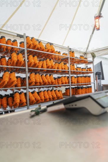 A tent with several shelves full of orange boots and a heater on the wall, Sindelfingen, Böblingen