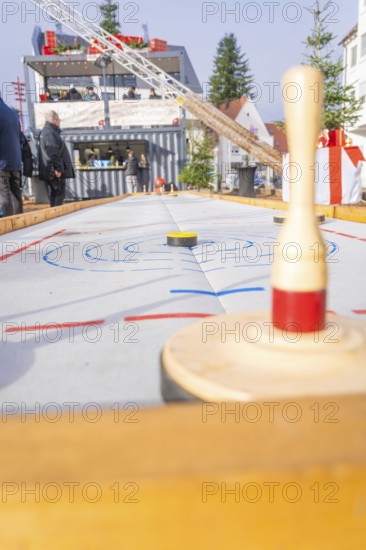 A wooden bowling game at a Christmas market with spectators standing in the background,