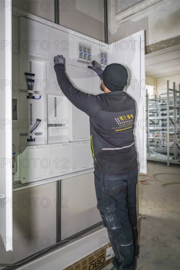 Technician working on a control cabinet, gloves, electrical cables, electrician, new building,