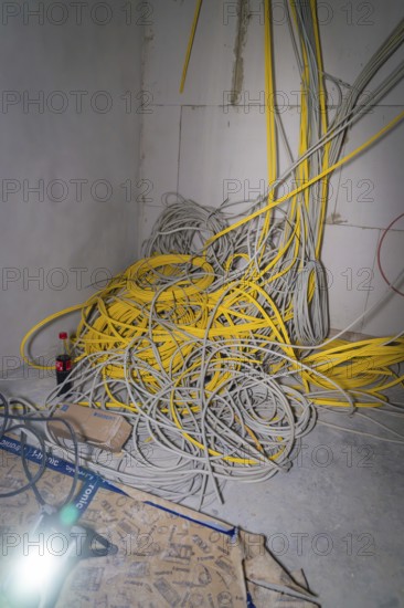 Disordered pile of yellow and gray cables in a corner of a room, electrician, new building, Germany