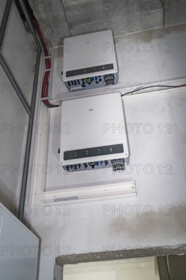 Two electronic devices are mounted on a wall, with visible cables and connections, electrician,
