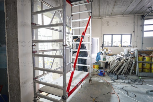 Interior on construction site with scaffolding, cables and building materials, lighting through