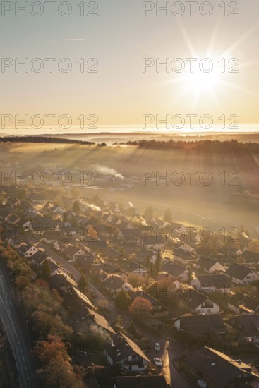 A village under golden sunlight with rays illuminating a warm autumn landscape, Gechingen, Hecken