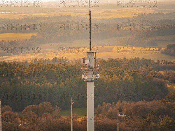 Close-up of a radio tower over a forest and field landscape in warm light, Gechingen, Hecken and