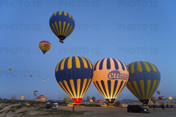 Several colorful hot air balloons rise in the morning sky over a vast landscape, Göreme National