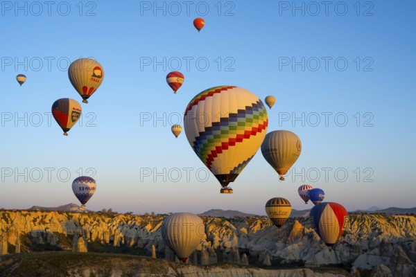 Colourful hot air balloons over a rocky landscape in soft morning light convey a sense of
