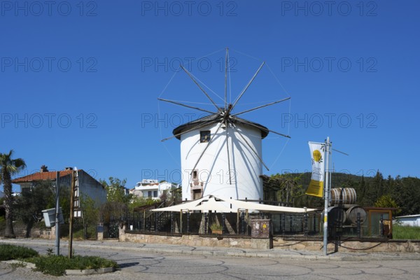 A traditional white windmill with wheels stands under bright blue sky, Cunda windmill, Alibey