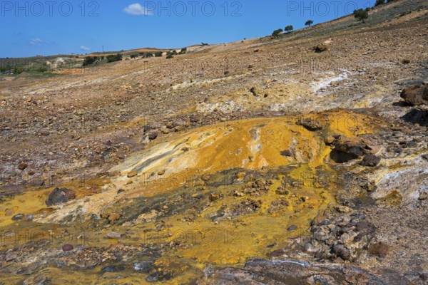 Area with yellow and brown rock formations under blue sky, geothermal area, rainbow rocks Tuzla,