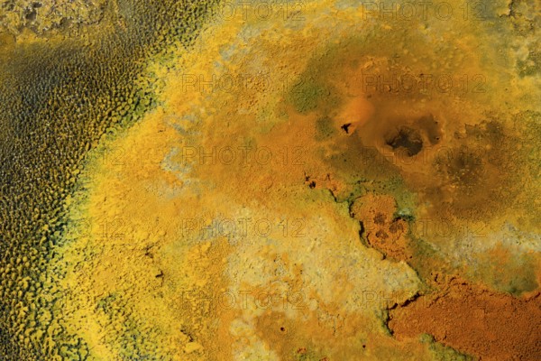 Detailed view of a mineral-rich volcanic landscape in intense shades of orange, geothermal area,