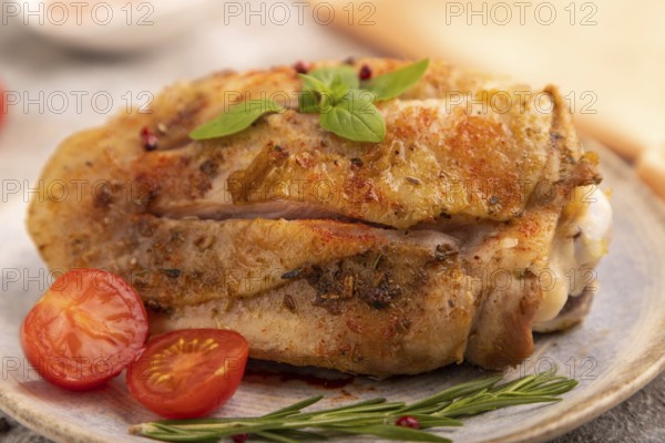 Fried Turkey Thigh with spices and rosemary on plate on brown concrete background and orange linen