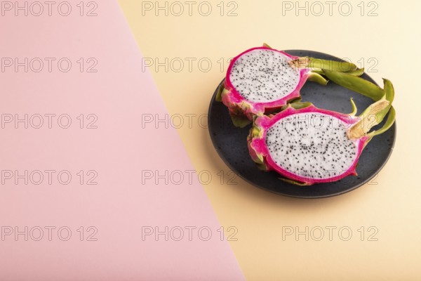 Ripe Pitaya on blue plate on pink and orange pastel paper background, side view, copy space,