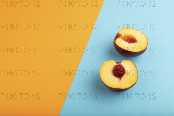 Peach Cut in half on orange and blue paper pastel background. Side view, copy space. healthy food,