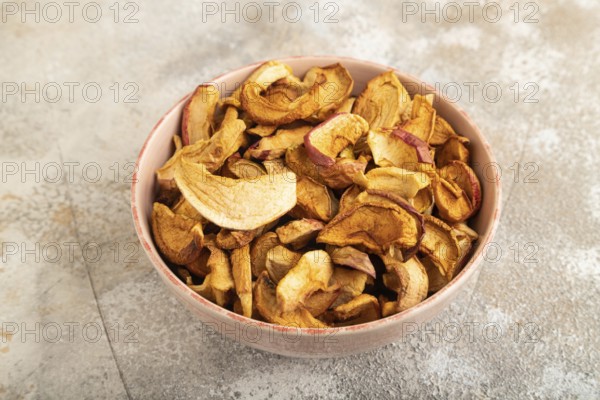 Dried Apples in ceramic bowl on brown concrete background. Side view, copy space, flat lay. healthy