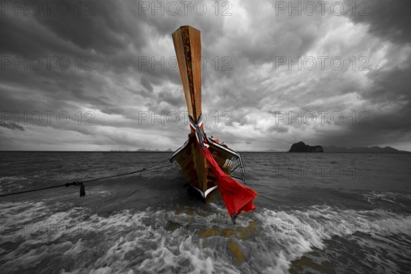 Longtail boat on the beach with dark rain clouds behind it, Koh Ngai island, Andaman Sea, Satun