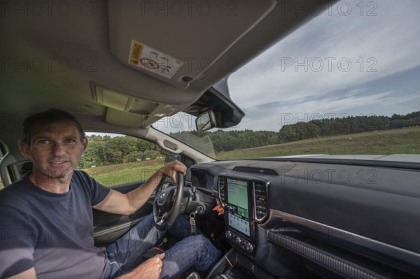 Young shepherd in car checks his flocks of sheep in nature reserves, Othenstorf,