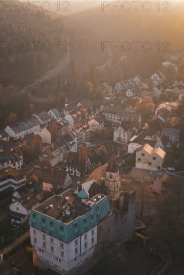 Aerial view of picturesque village in morning light surrounded by forests and hills,