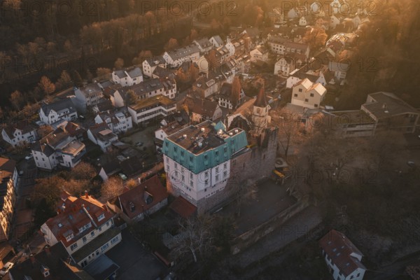 Aerial view of a village in the golden light of sunset, with a distinctive castle, Dillweisenstein,